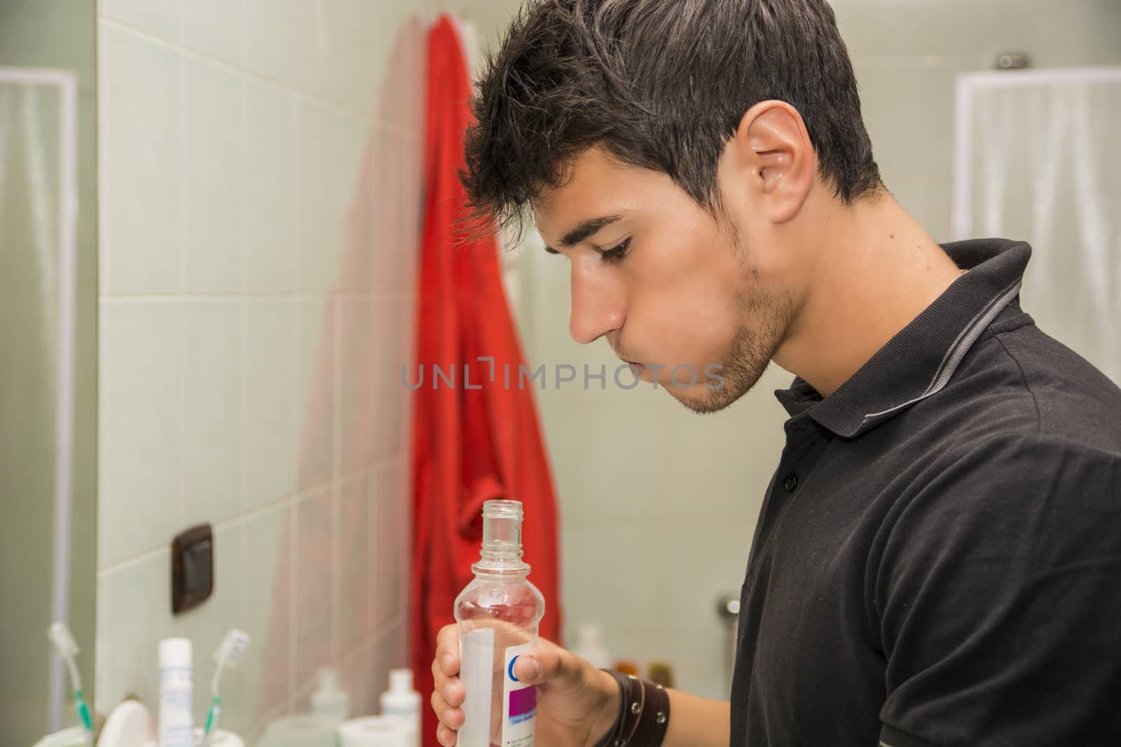 Young Man Rinsing with Mouth Wash in Bathroom by artofphoto
