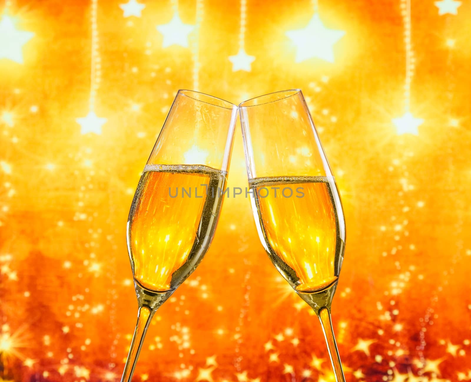 a pair of champagne flutes with golden bubbles make cheers on golden stars light background with space for text