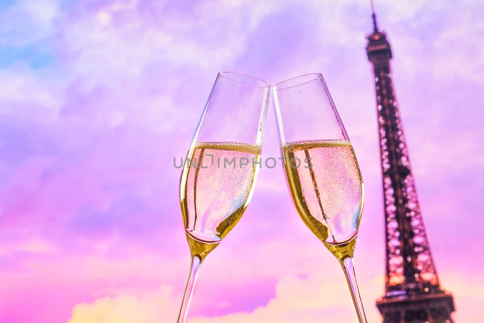 a pair of champagne flutes with golden bubbles make cheers on sunset blur tower Eiffel background valentine day concept