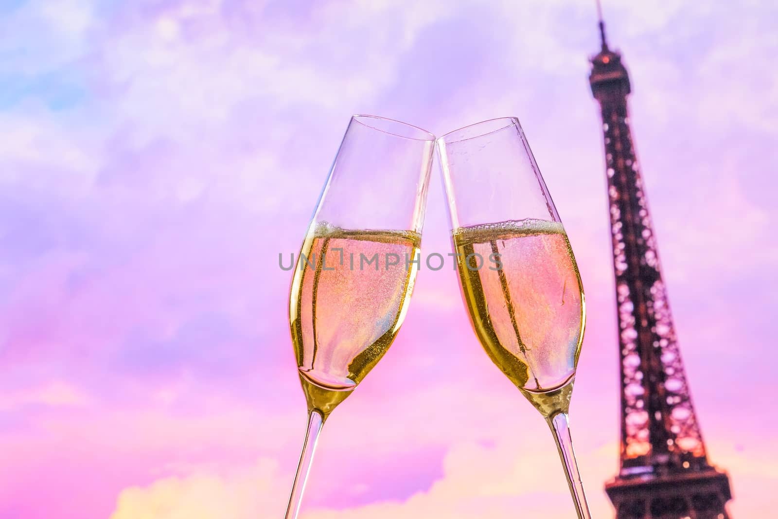 a pair of champagne flutes with golden bubbles make cheers on blur tower Eiffel background valentine day concept