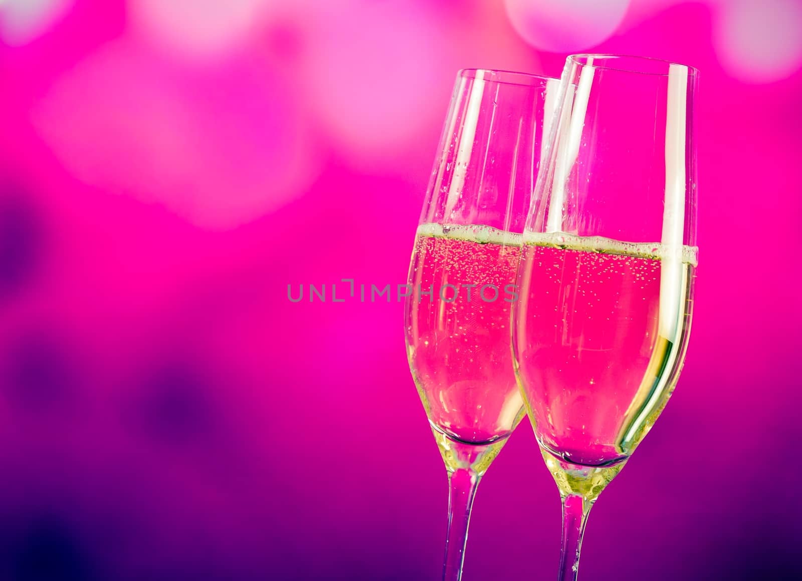 champagne flutes with gold bubbles on blue and violet tint light background with space for text