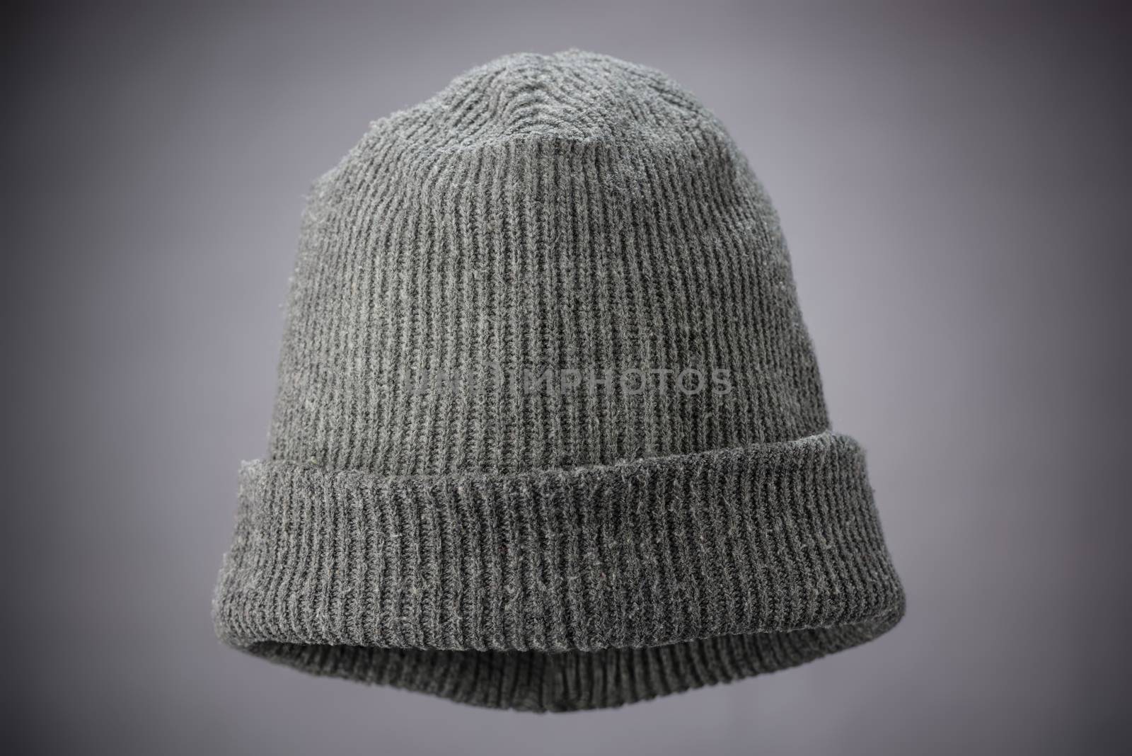 A studio shot of a grey knit cap suspended on a grey background lit with a natural vignette.