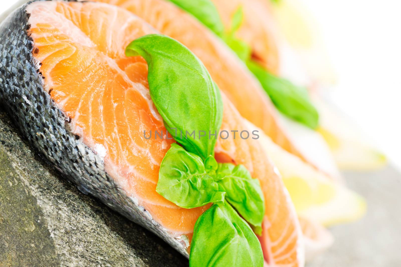 Salmon cuts on stone with basil and lemon