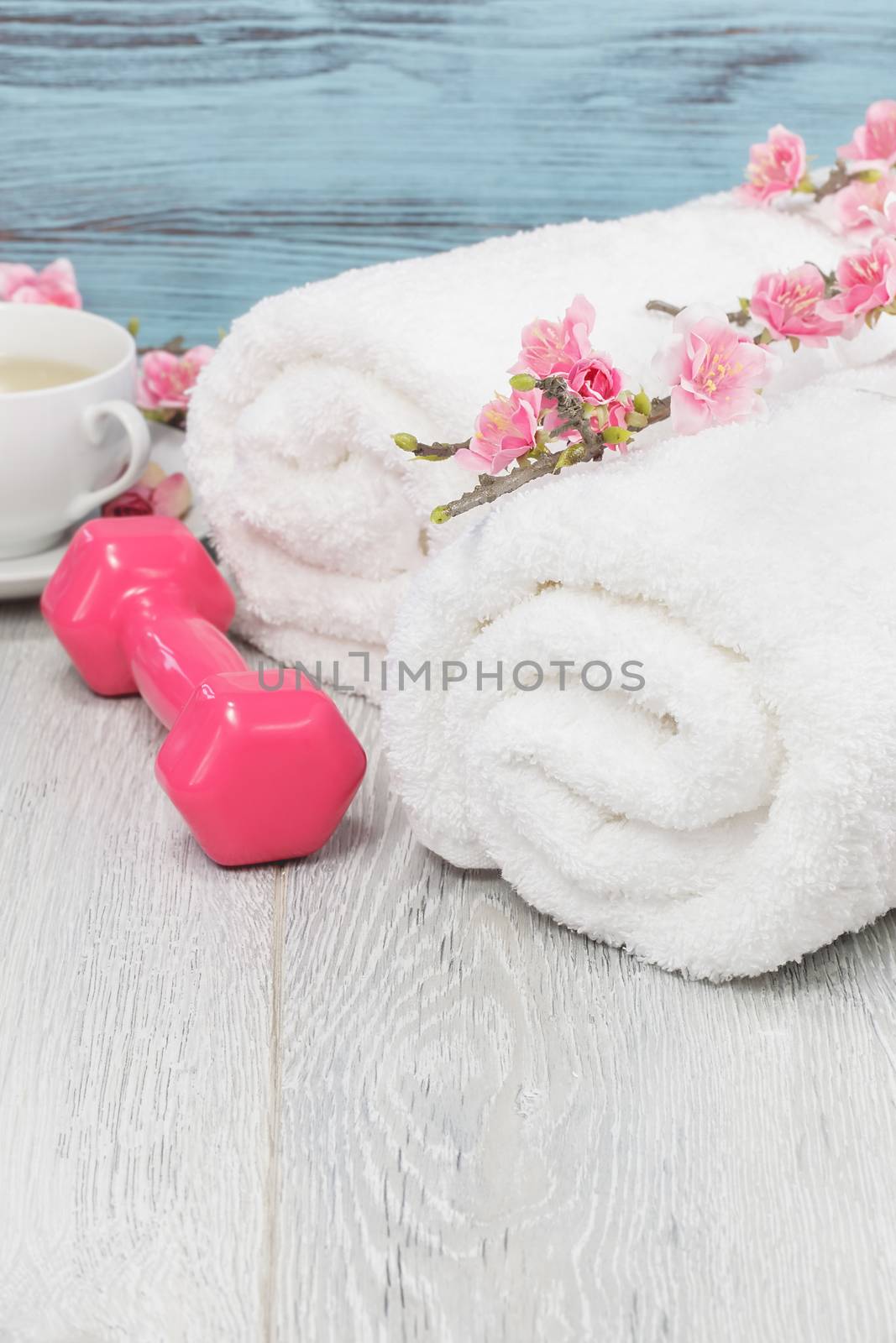 Fitness and healthy living concept with sport- hand weights, towel and tea. Macro photograph with shallow depth of field