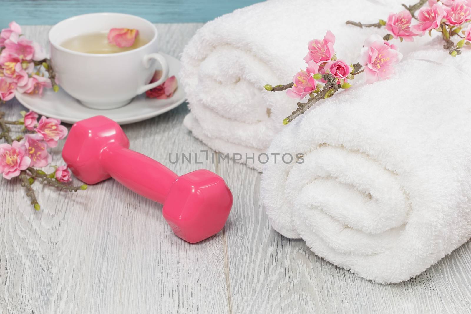 Fitness and healthy living concept with sport- hand weights, towel and tea. Macro photograph with shallow depth of field