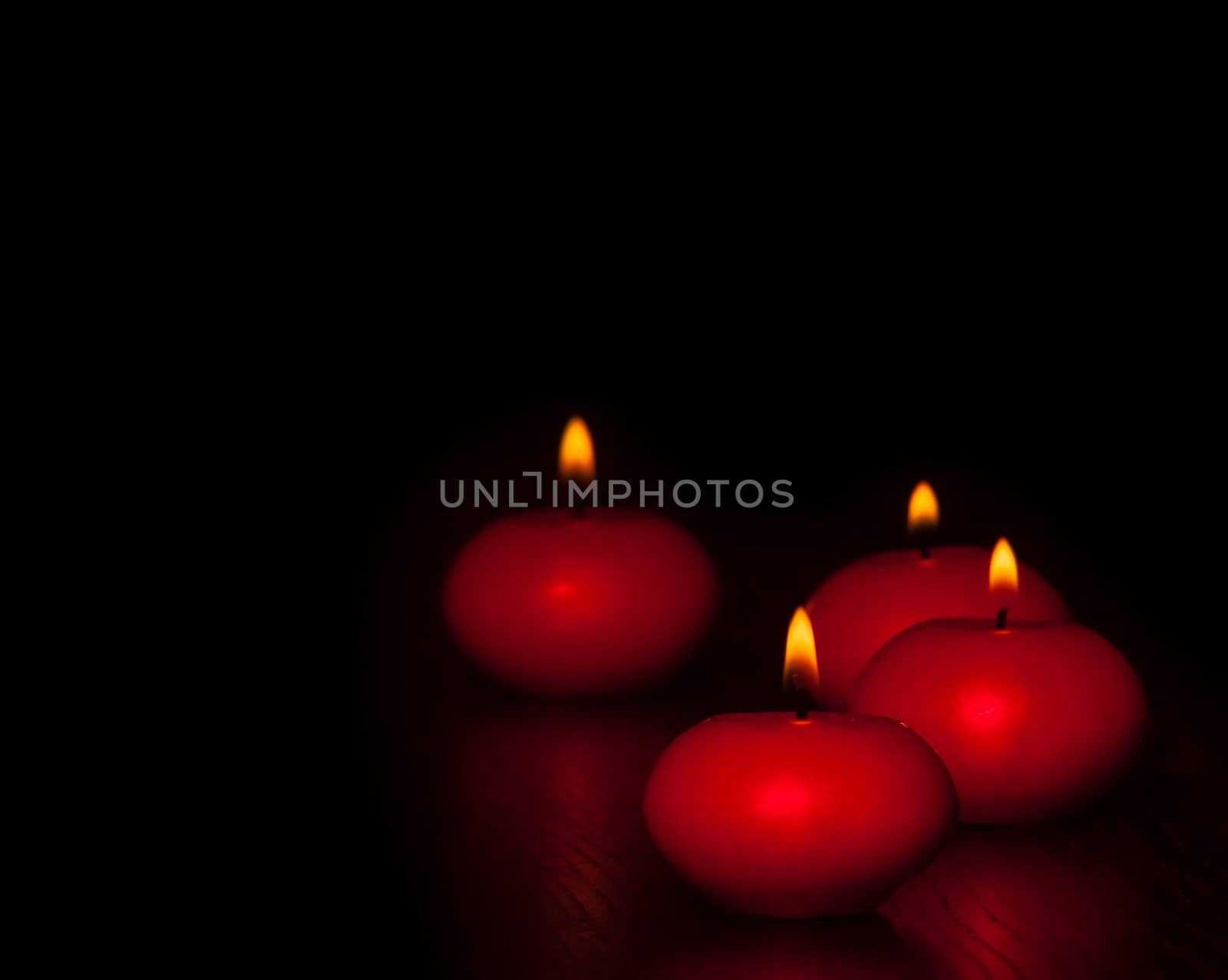 red candles with flame on wood and black background, dark atmospere by donfiore