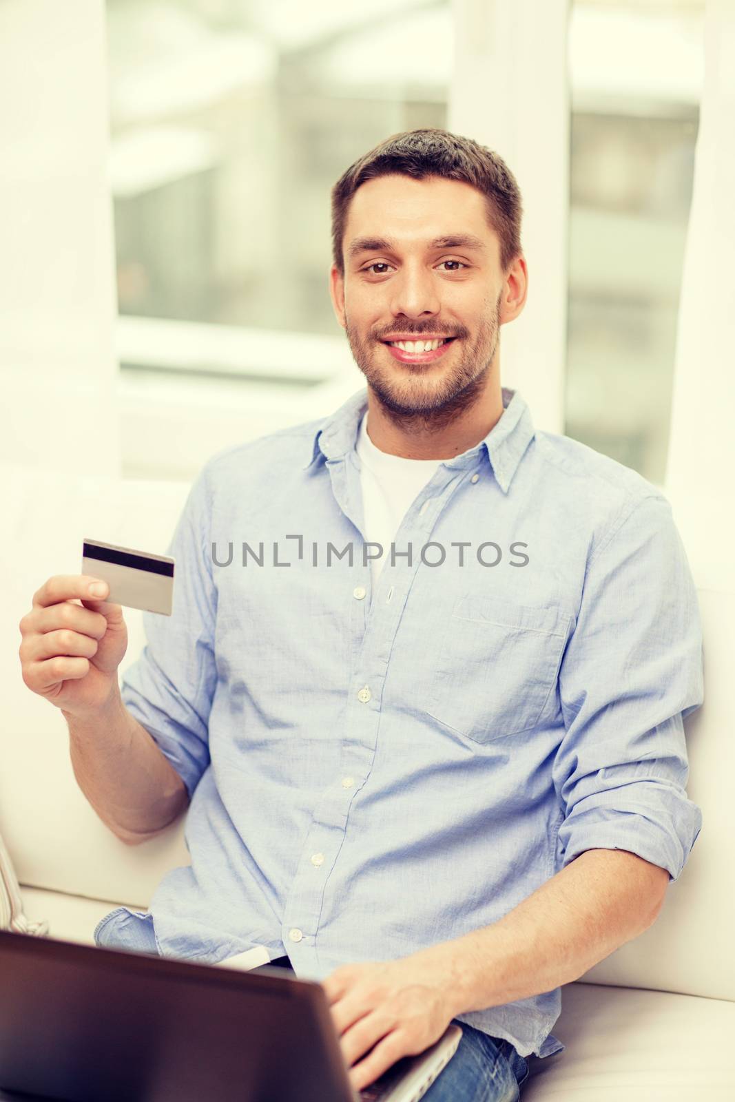 technology, home and lifestyle concept - smiling man working with laptop and credit card at home