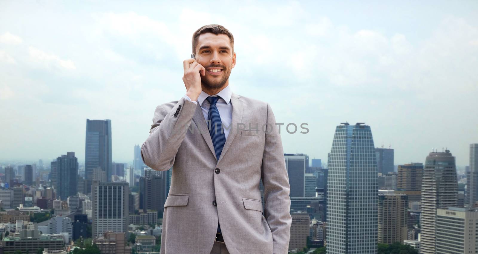 smiling businessman with smartphone in city by dolgachov