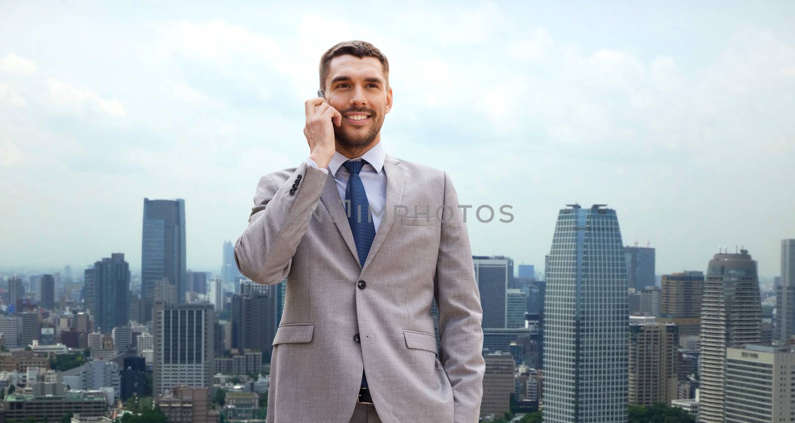 business, technology, communication and people concept - smiling businessman with smartphone talking over city background