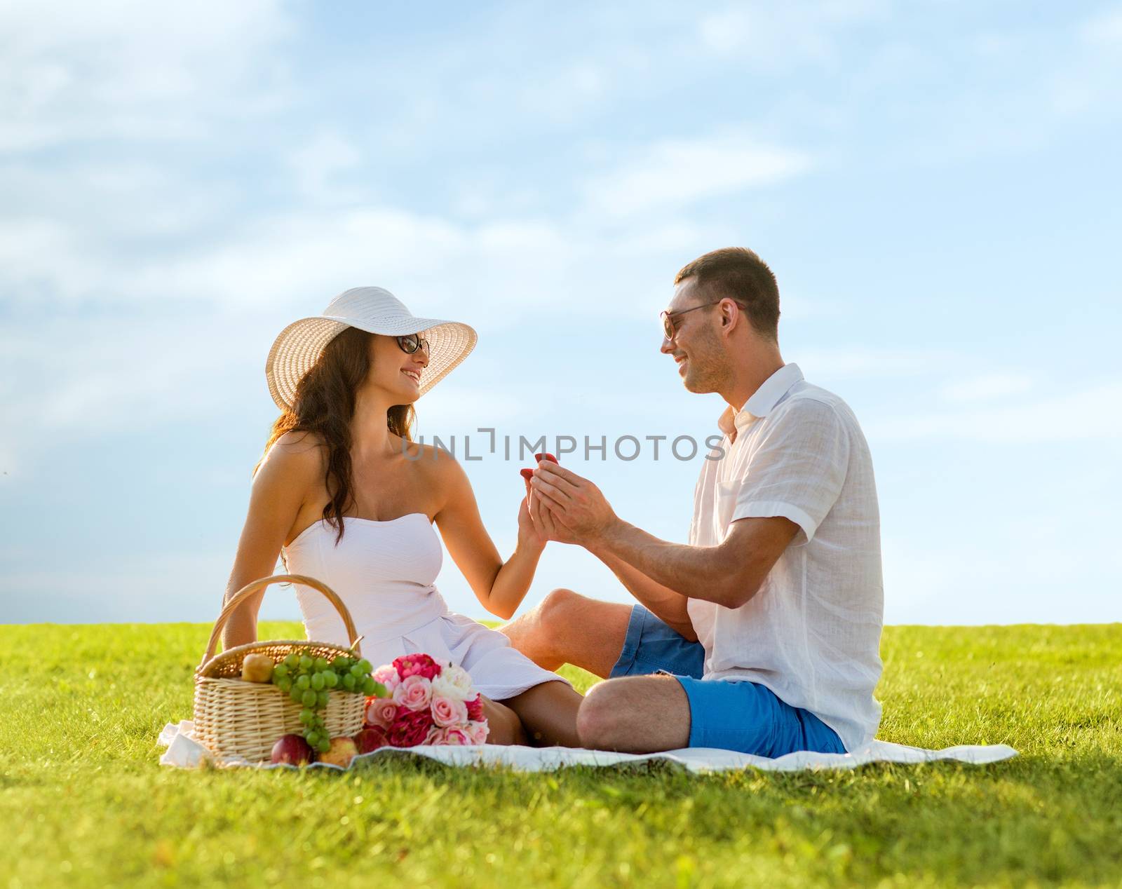 smiling couple with small red gift box on picnic by dolgachov