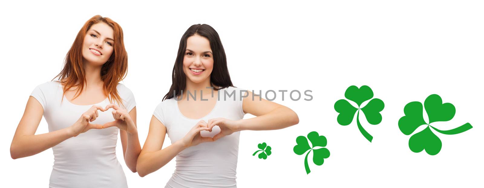 smiling girls showing heart gesture with shamrock by dolgachov