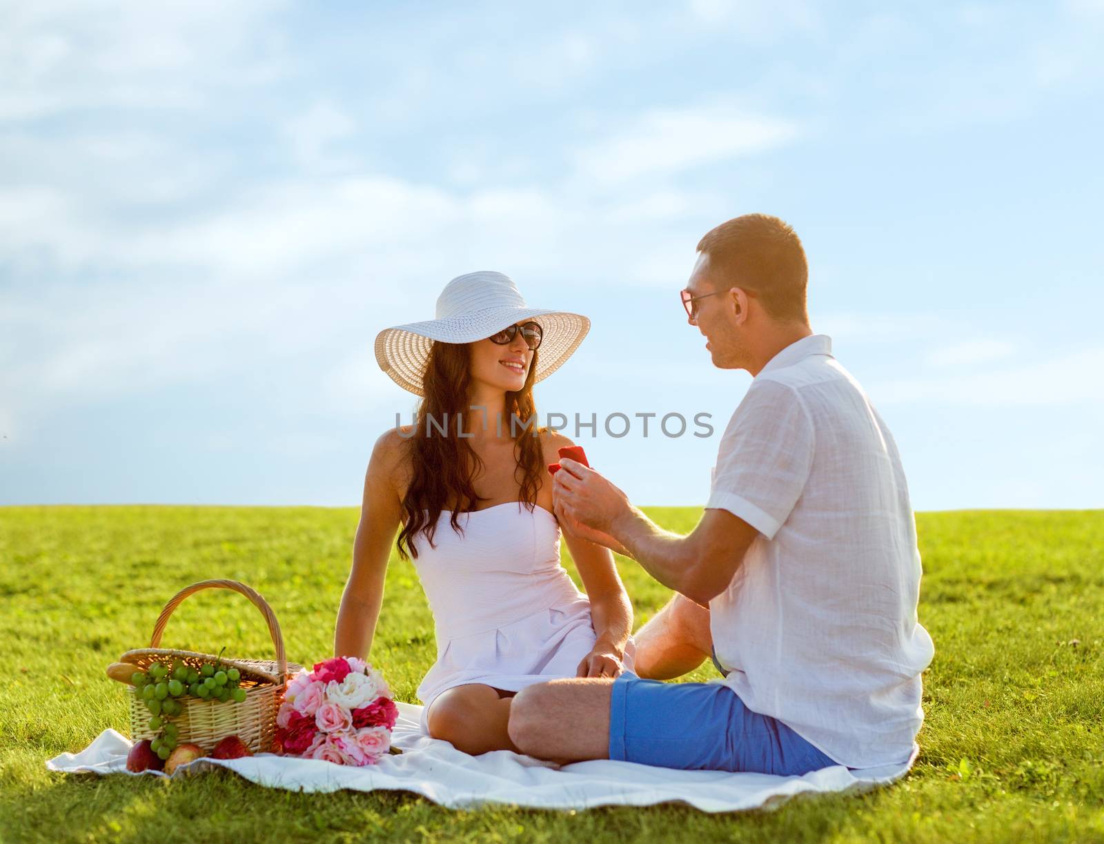 smiling couple with small red gift box on picnic by dolgachov