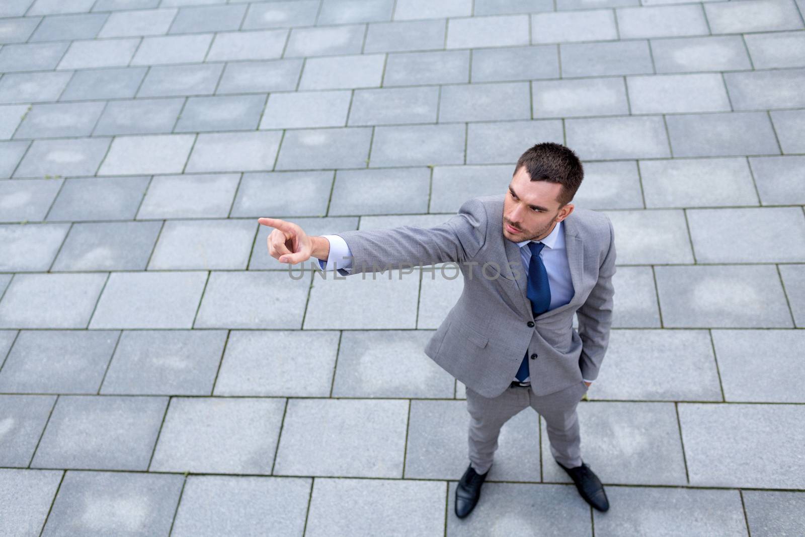 business, development and people and concept - young smiling businessman pointing finger outdoors from top