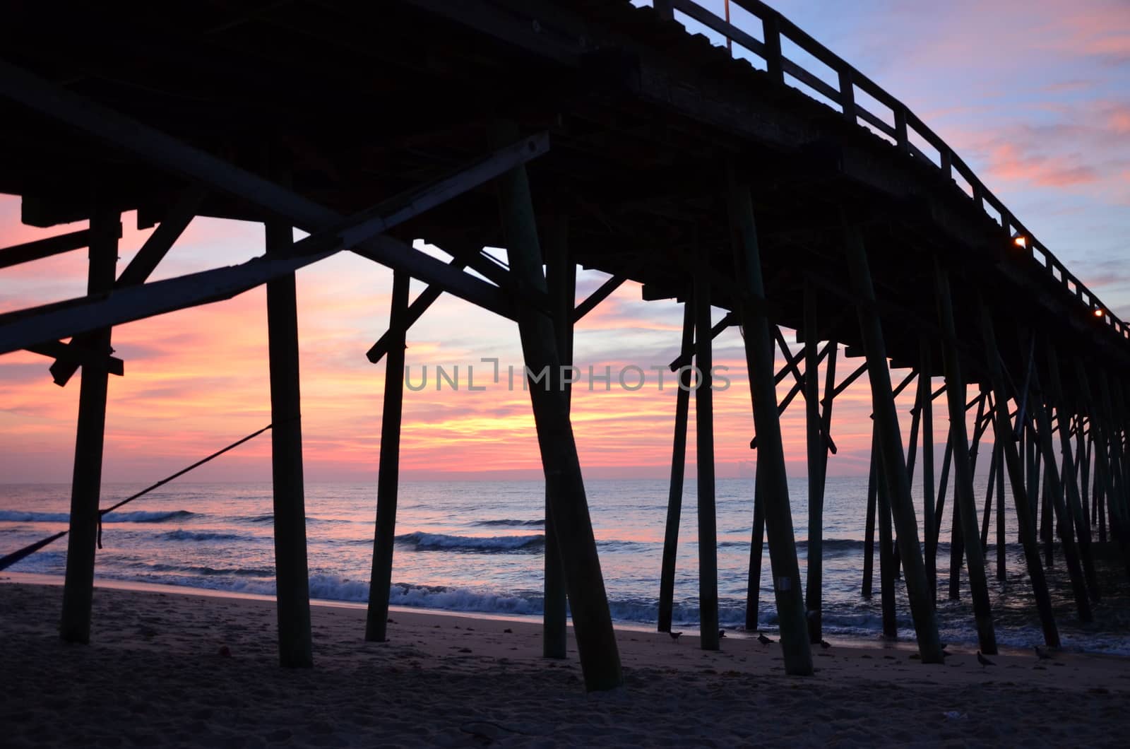 View under the pier. Sunrise at Kure Beach North Carolina on a warm summer morning.