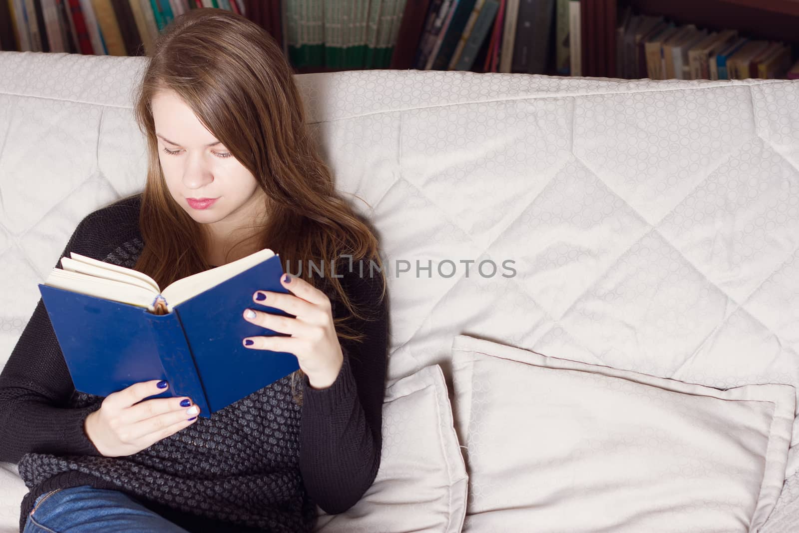 young woman reading a book on the couch