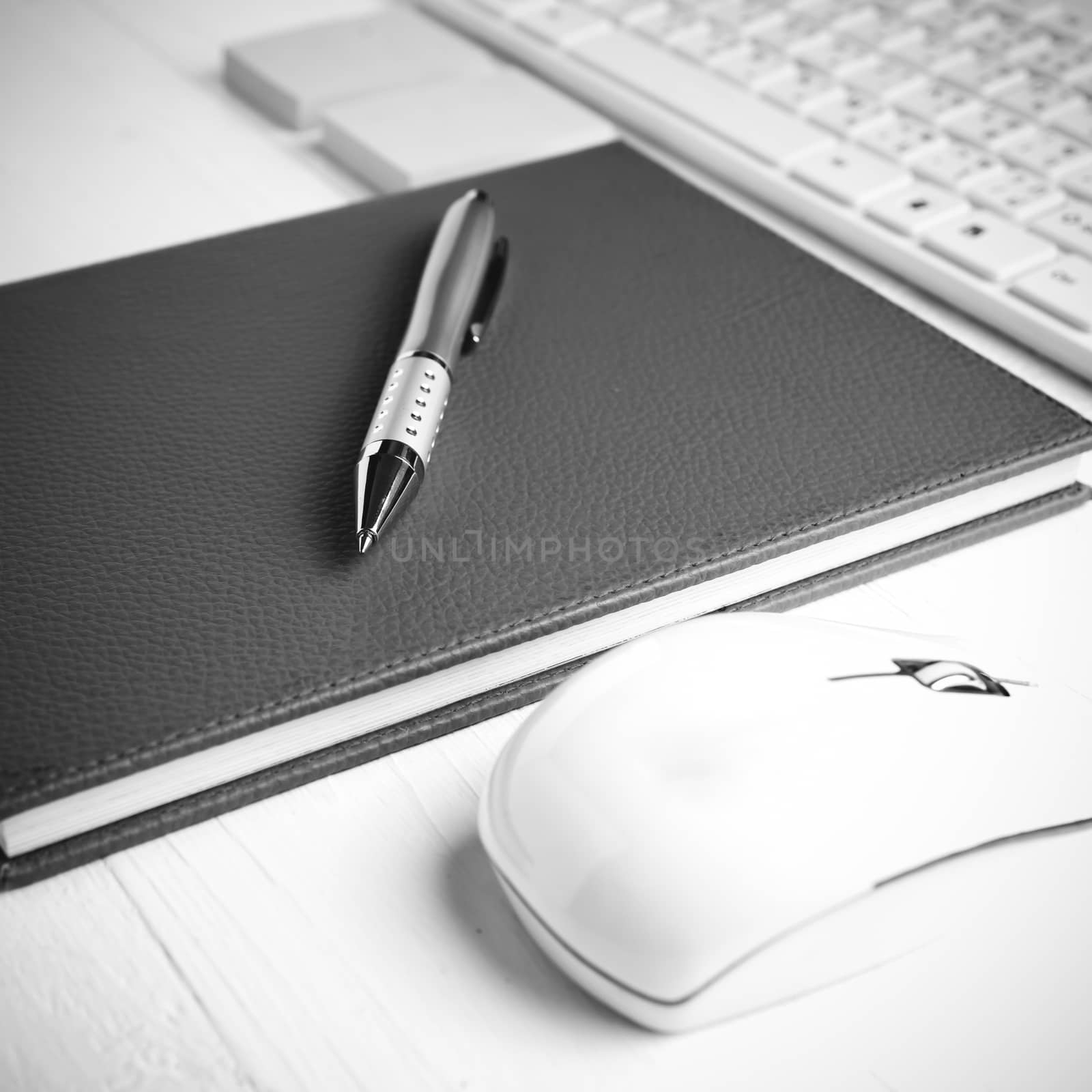 computer and brown notebook with office supplies on white table black and white style