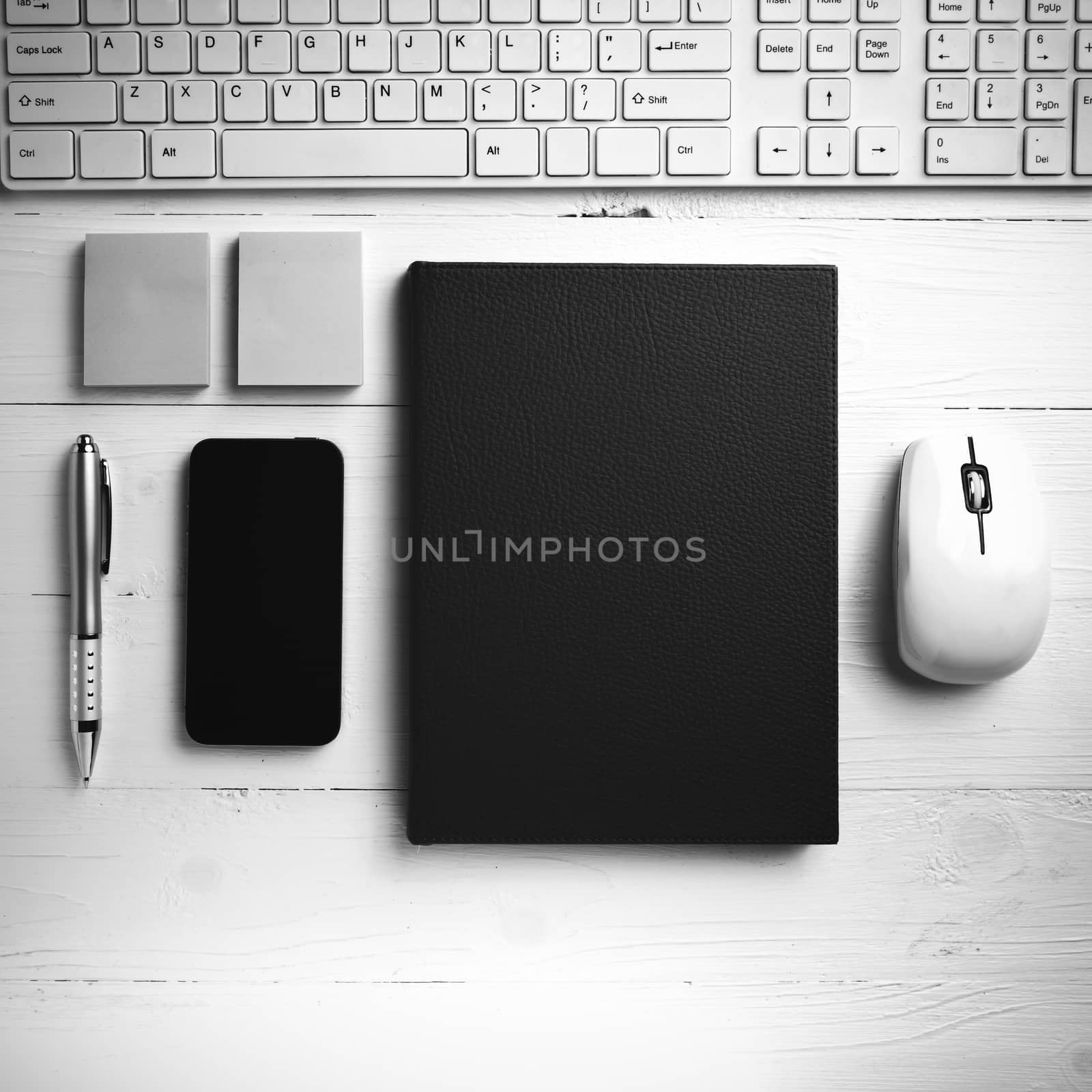 computer and brown notebook with office supplies on white table black and white style