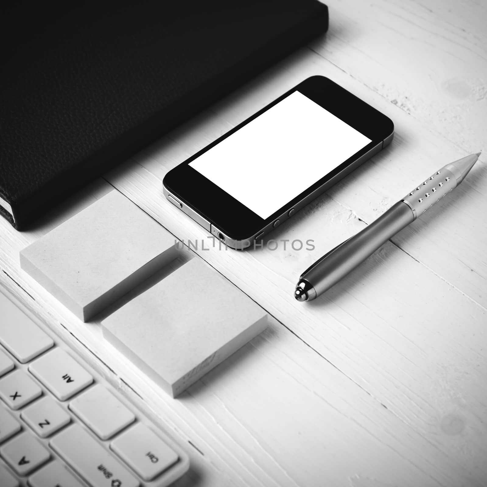 computer and brown notebook with office supplies on white table black and white style