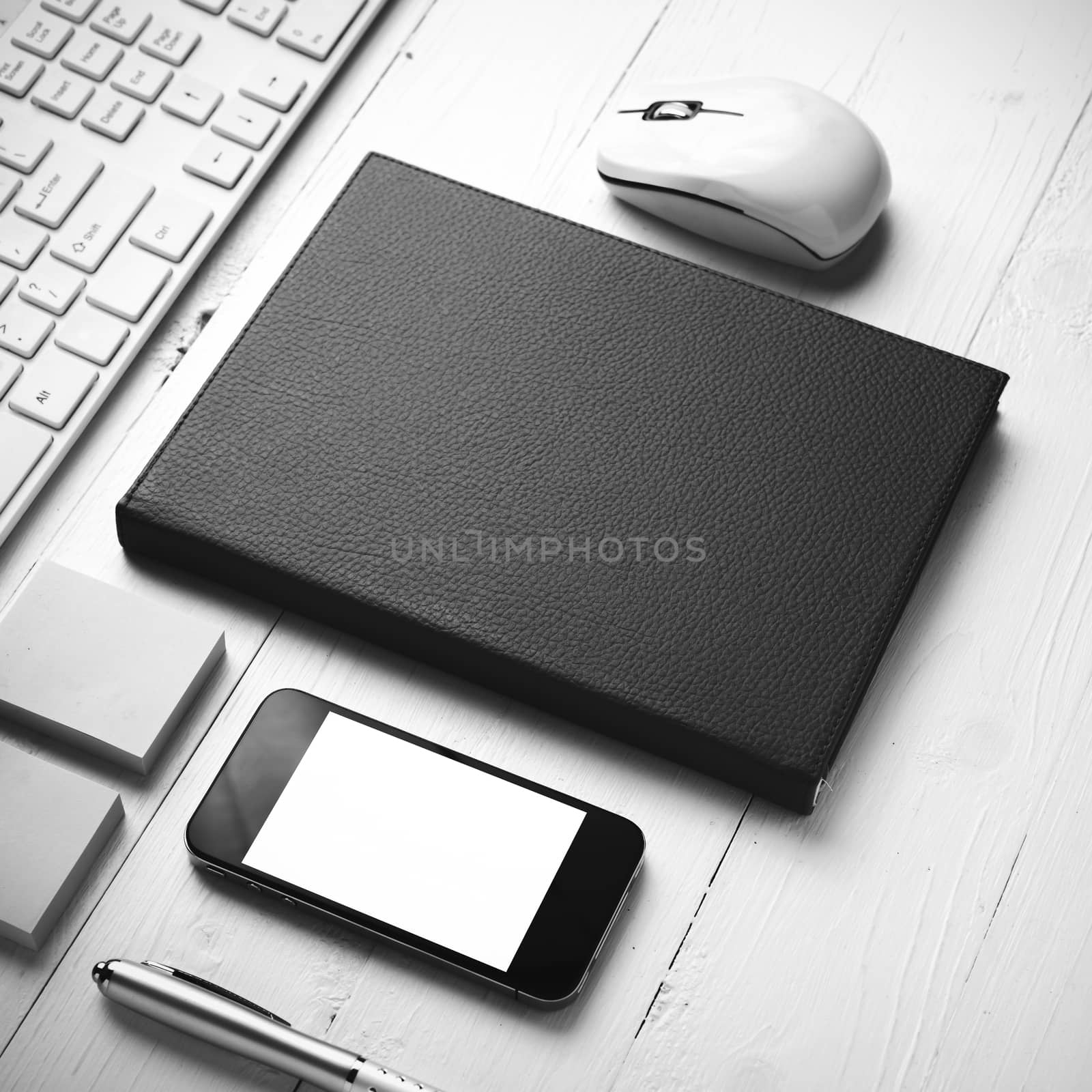 computer and brown notebook with office supplies on white table black and white style