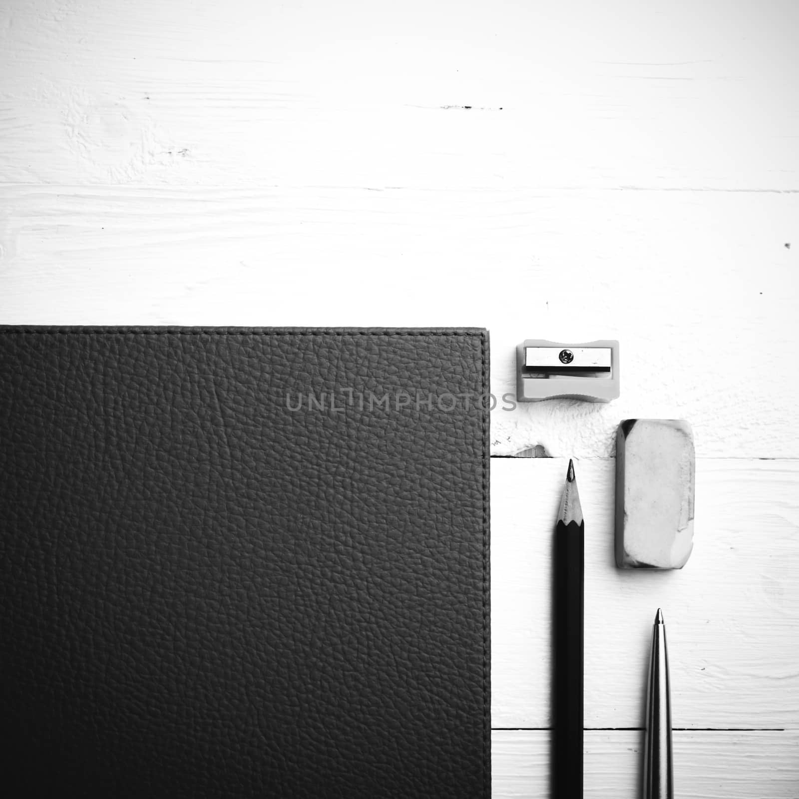 brown notebook with office supplies on white table view from above black and white style