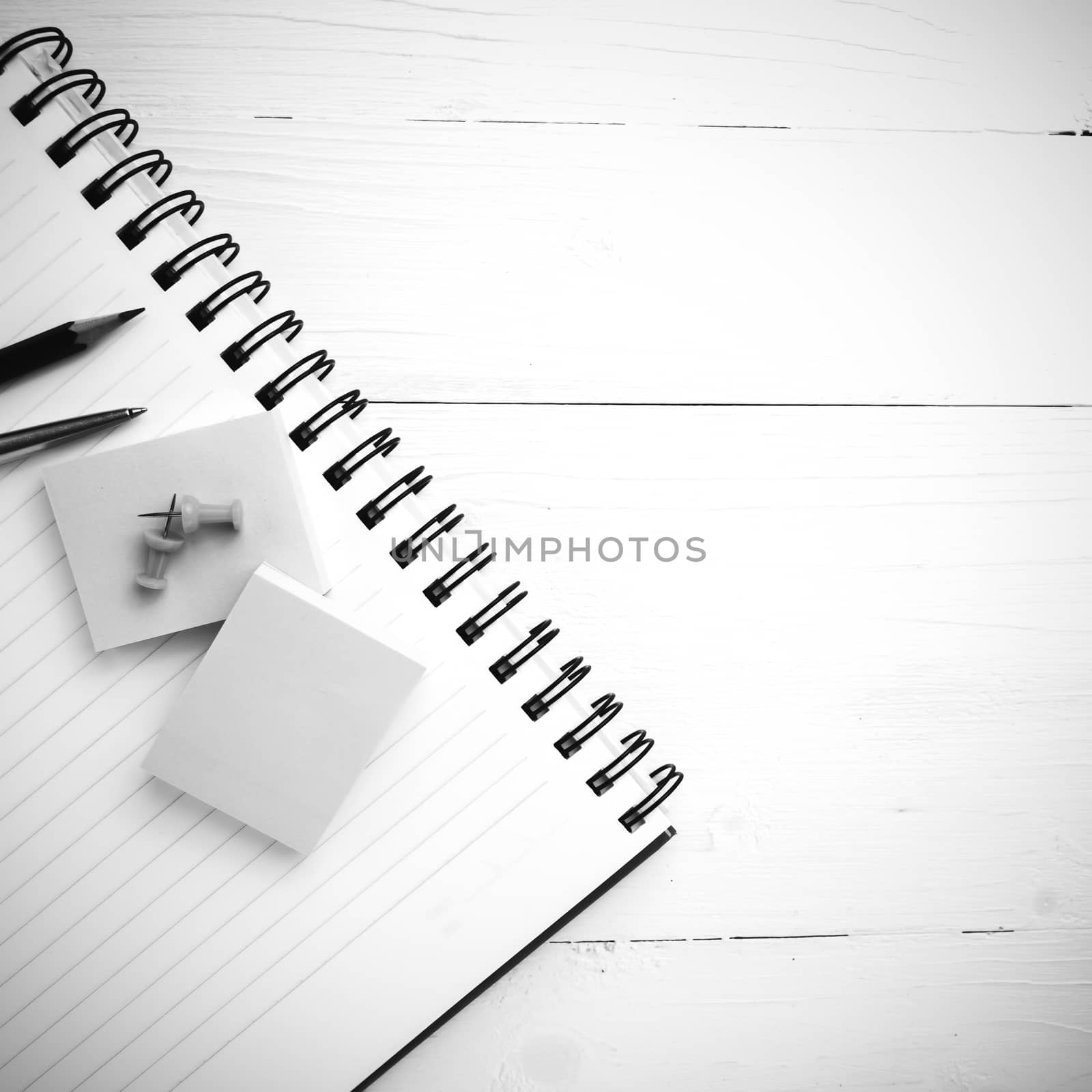 notepad with office supplies on white table view from above black and white style