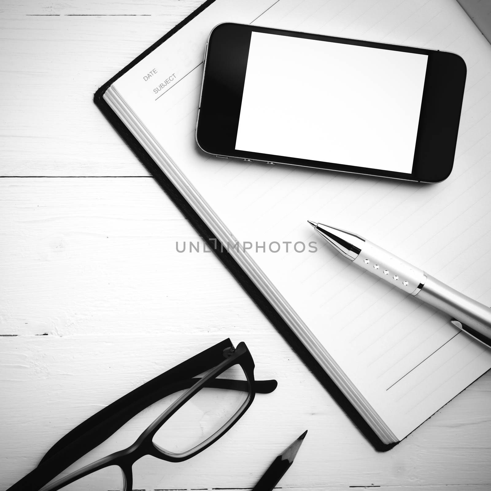 smart phone on notebook over white table black and white style
