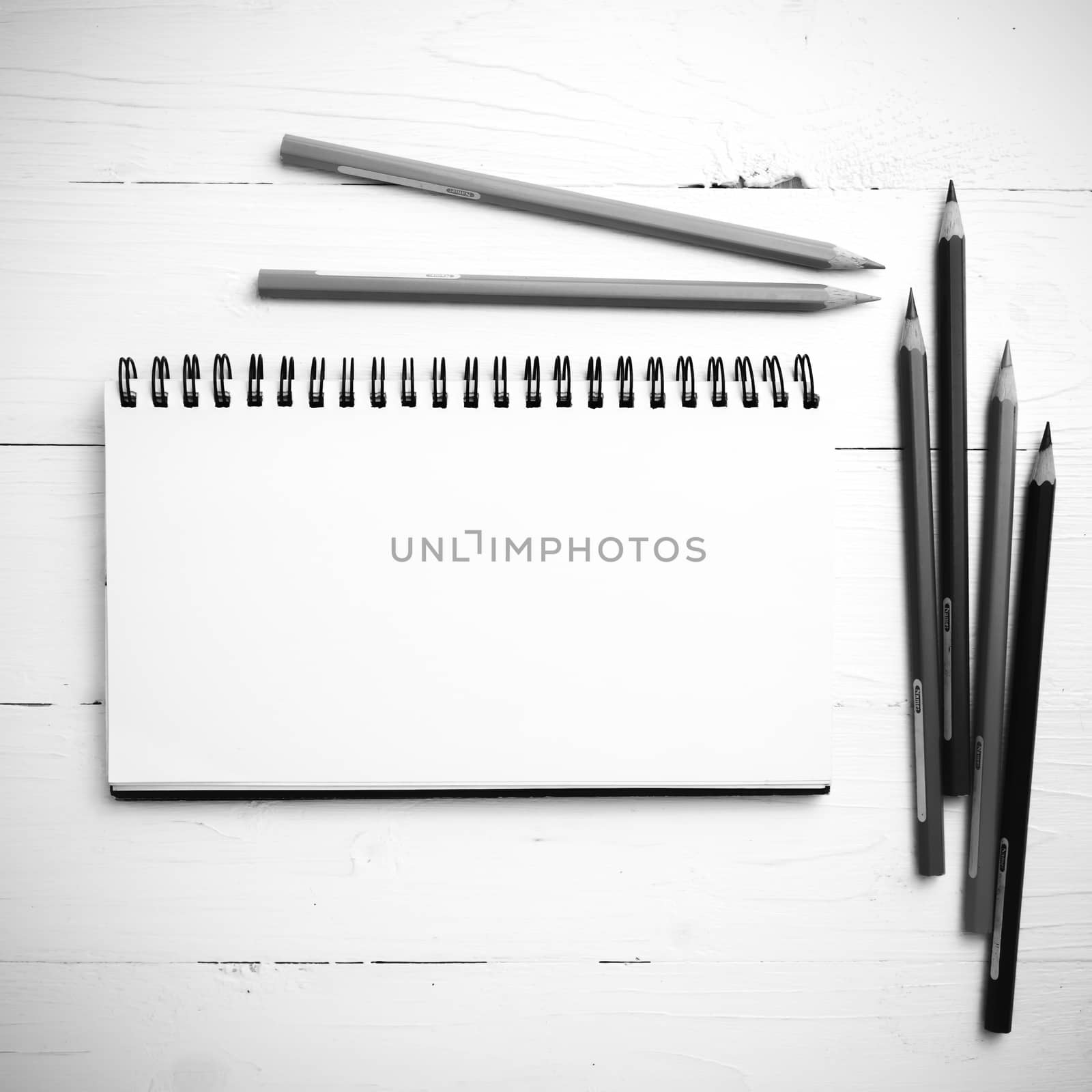 notepad with color pencil on white table view from above black and white color style