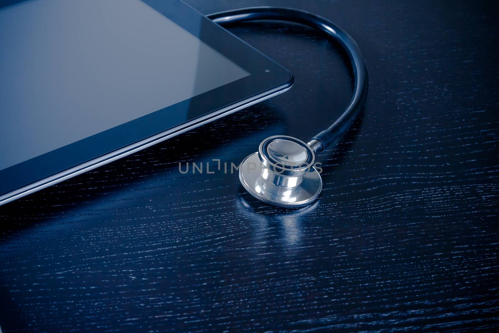 medical stethoscope on modern digital tablet pc in laboratory on wood table. Concept of medical or research theme