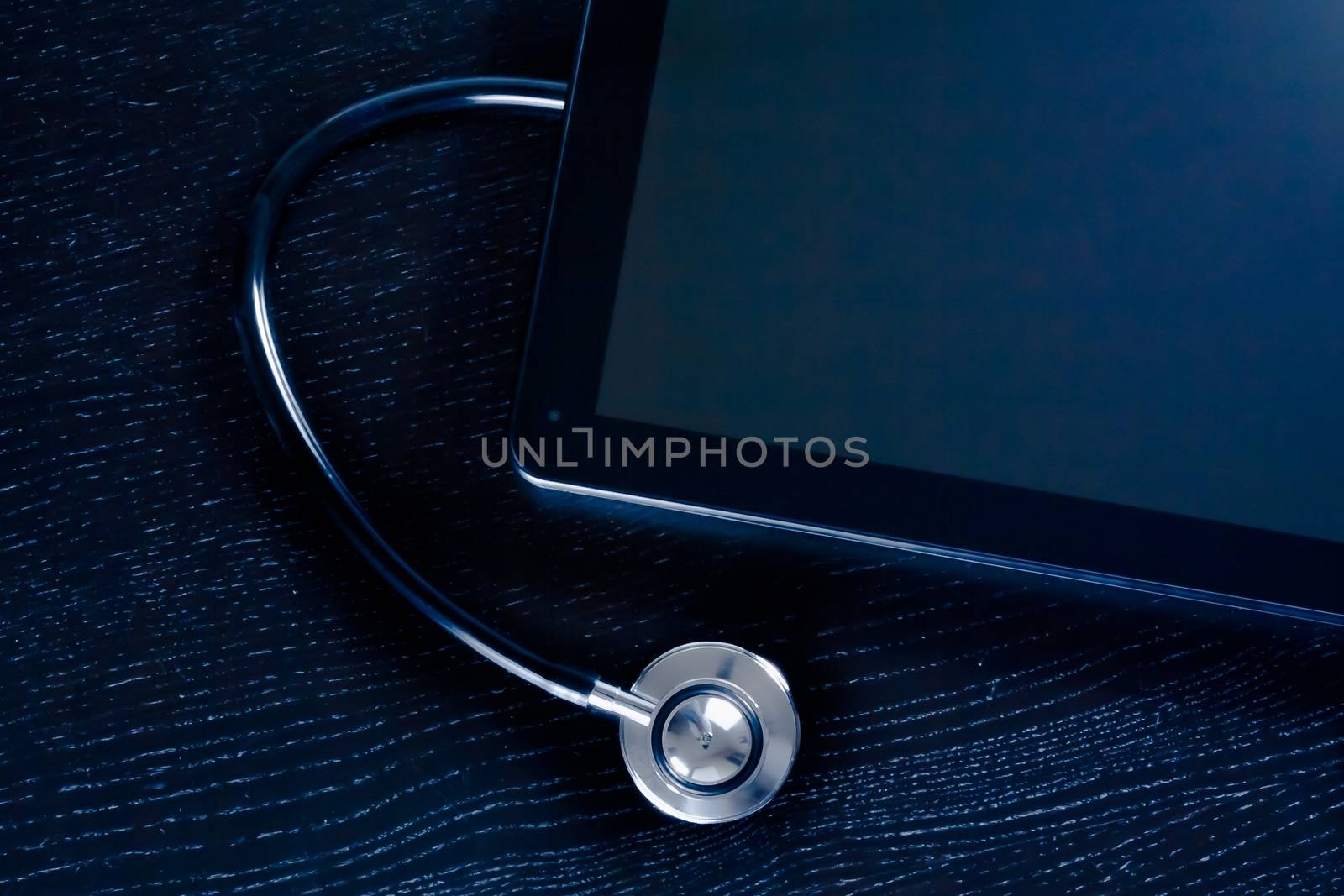 top of view of medical stethoscope near modern digital tablet pc in laboratory on wood table by donfiore