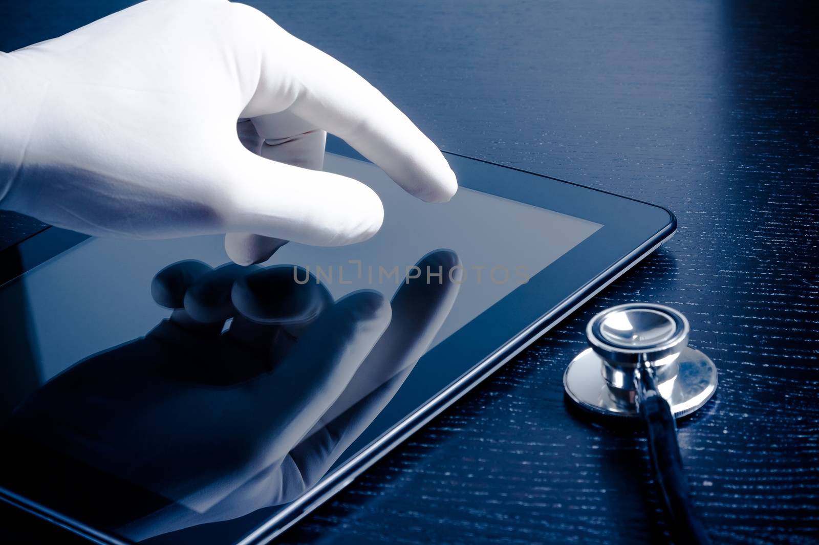 hand in medical glove touching modern digital tablet pc near stethoscope on black wood table. Concept of medical or research theme