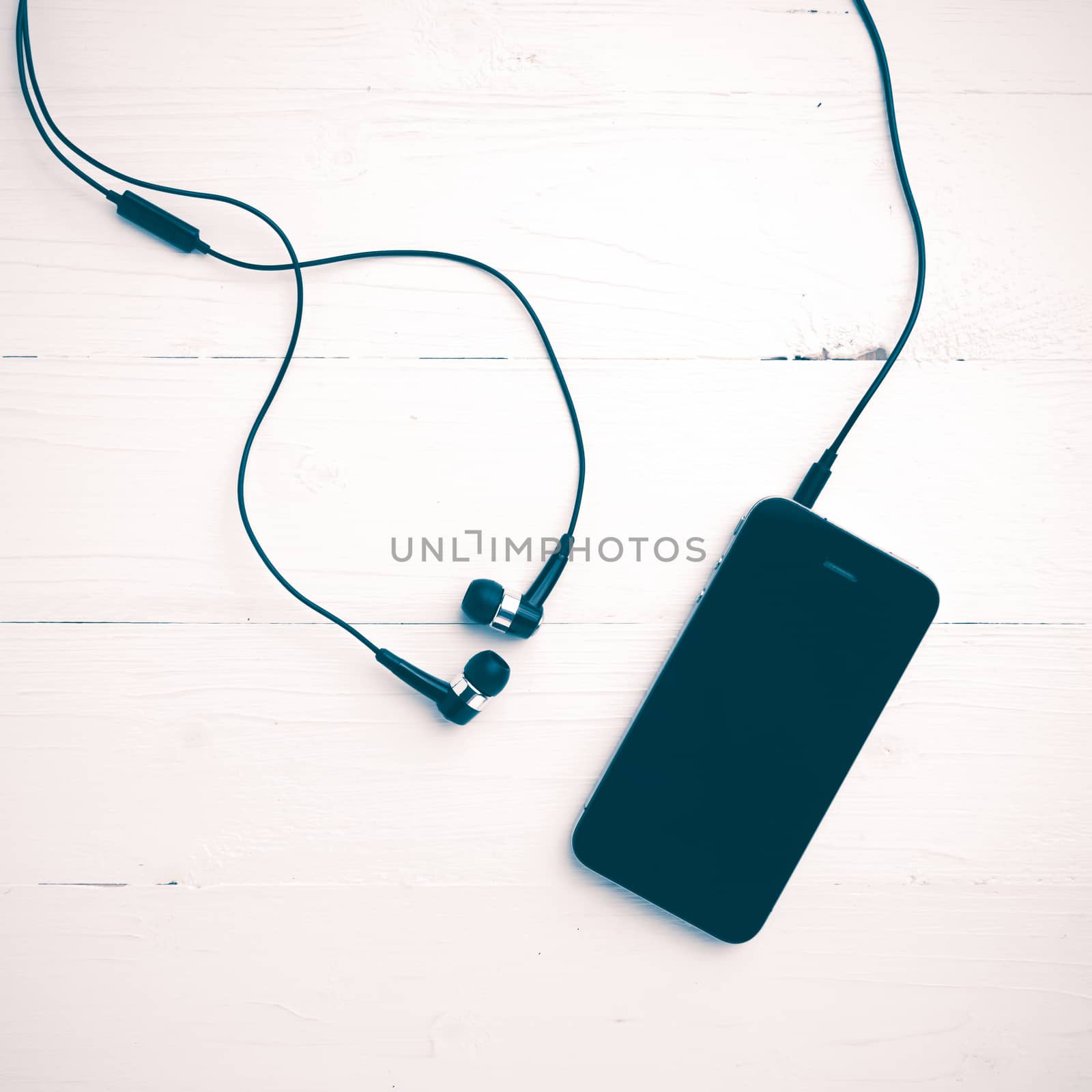 cellphone with earphone over white table vintage style