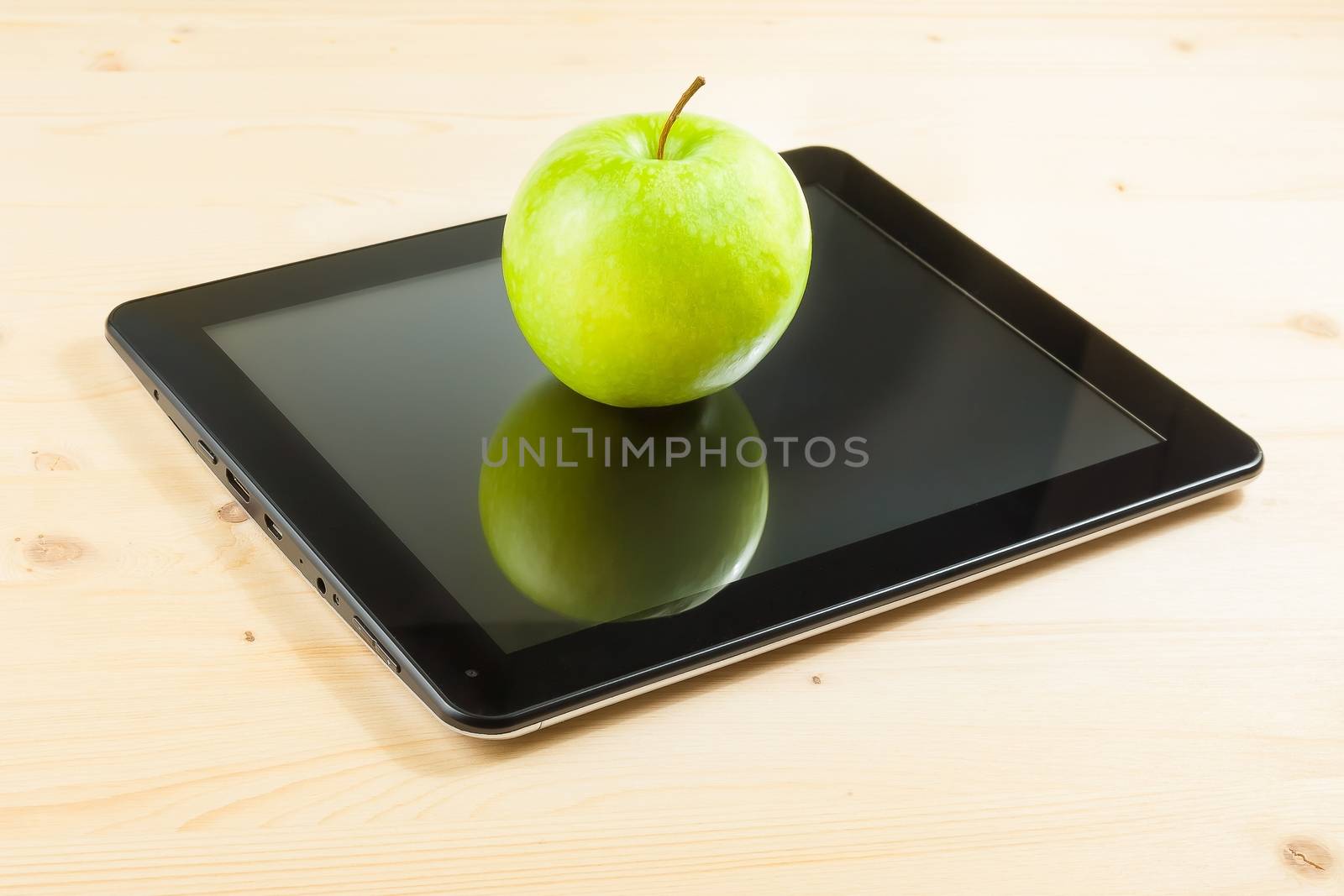 green apple on digital tablet pc on wood table by donfiore