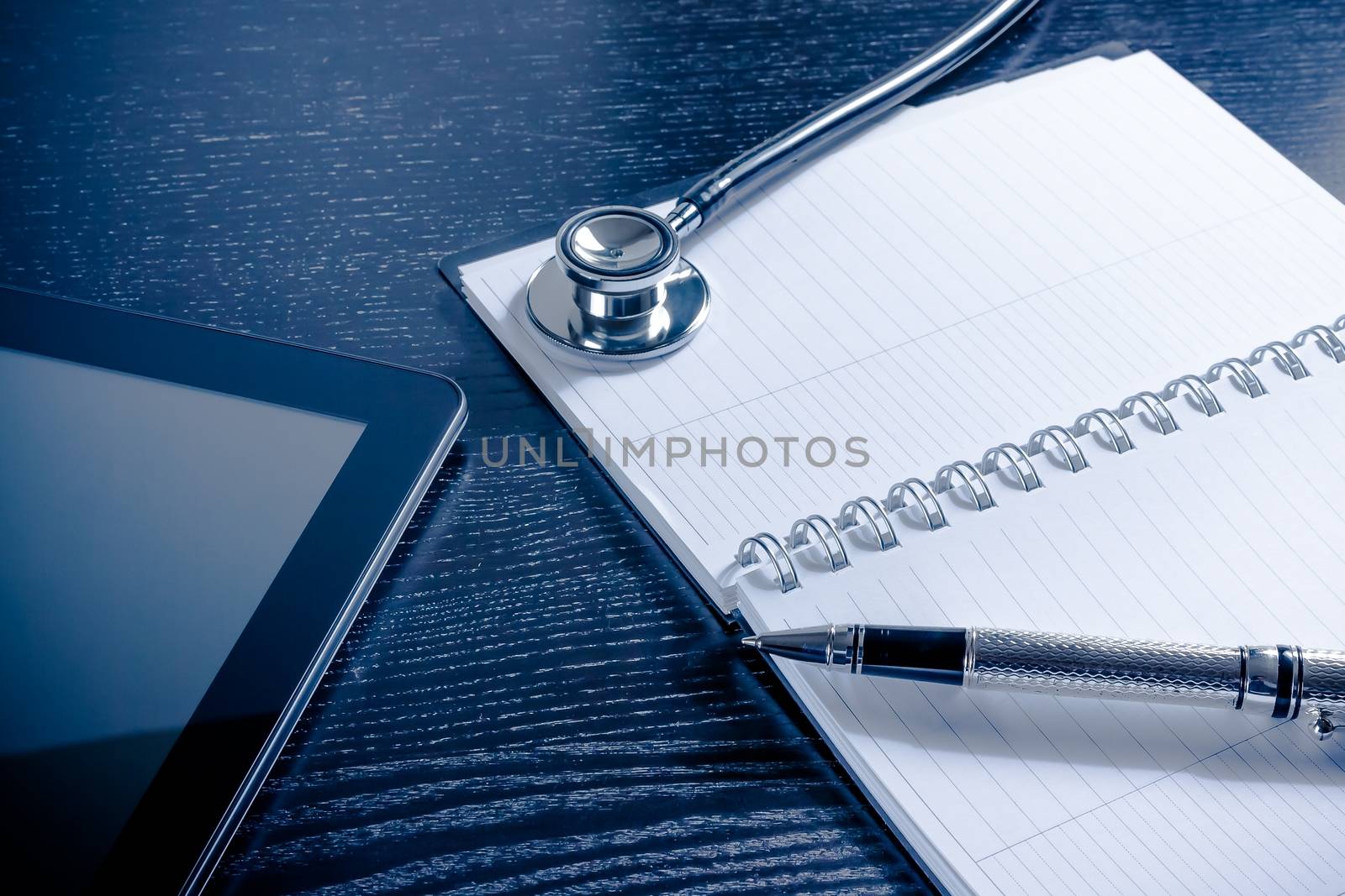 stethoscope on notes near modern digital tablet pc on wood table. Concept of medical or research theme
