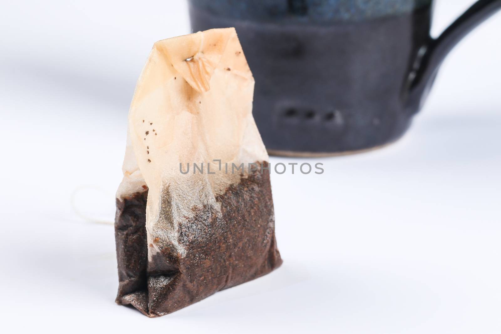 used tea bag with tea cup on white background