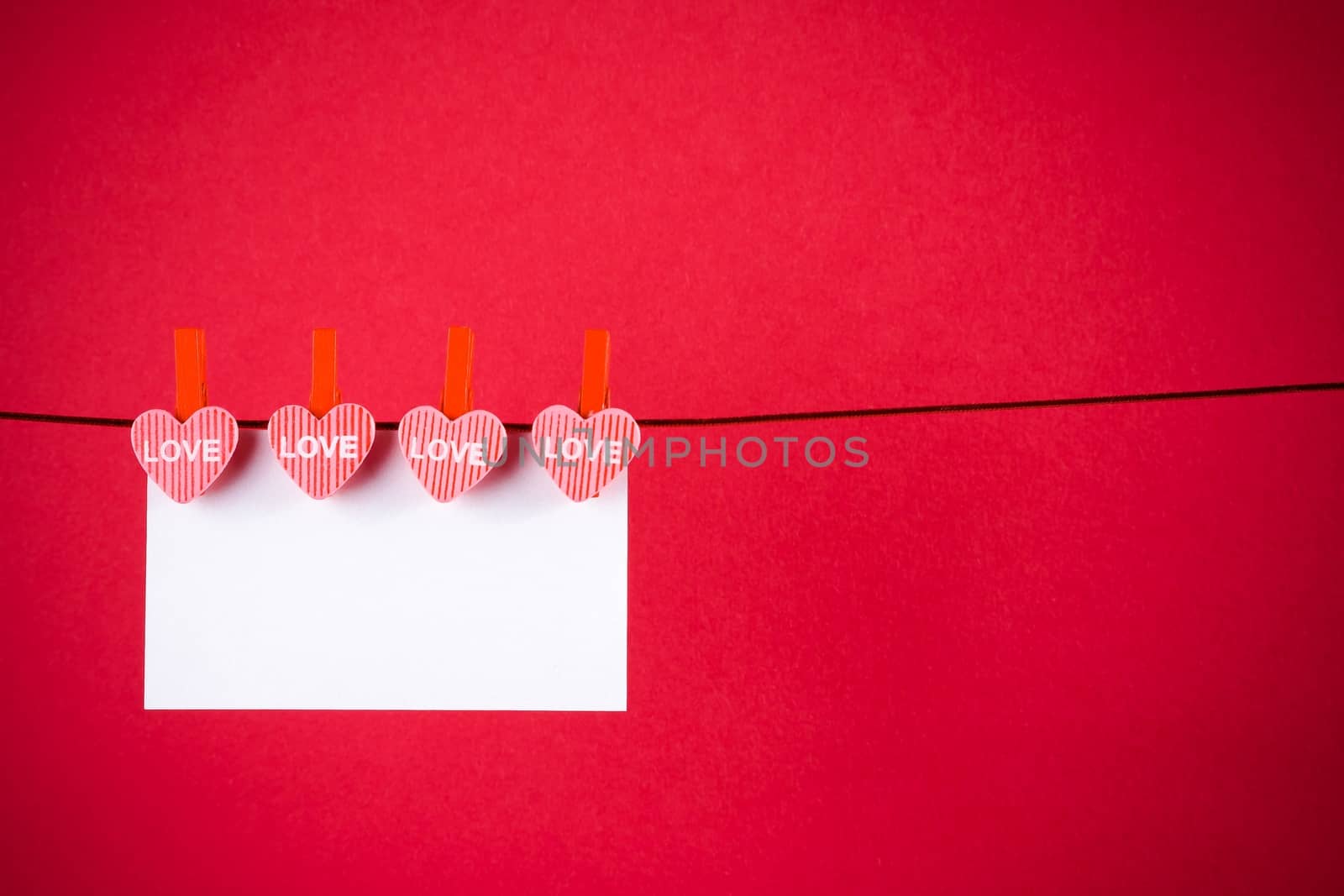 decorative red hearts with greeting card hanging on red background with space for text, concept of valentine day
