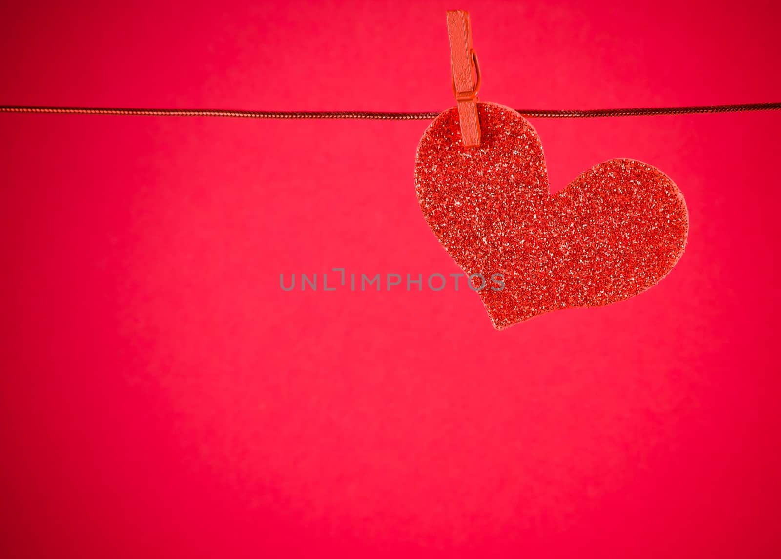 decorative red heart hanging on red background with space for text, concept of valentine day