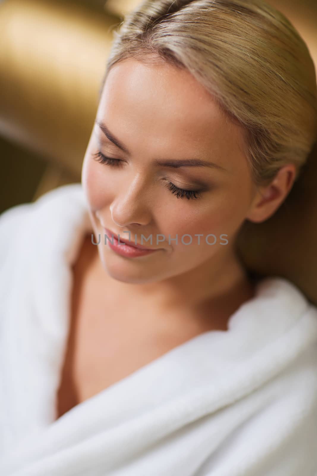people, beauty, healthy lifestyle and relaxation concept - close up of beautiful young woman resting on chair in bath robe at spa