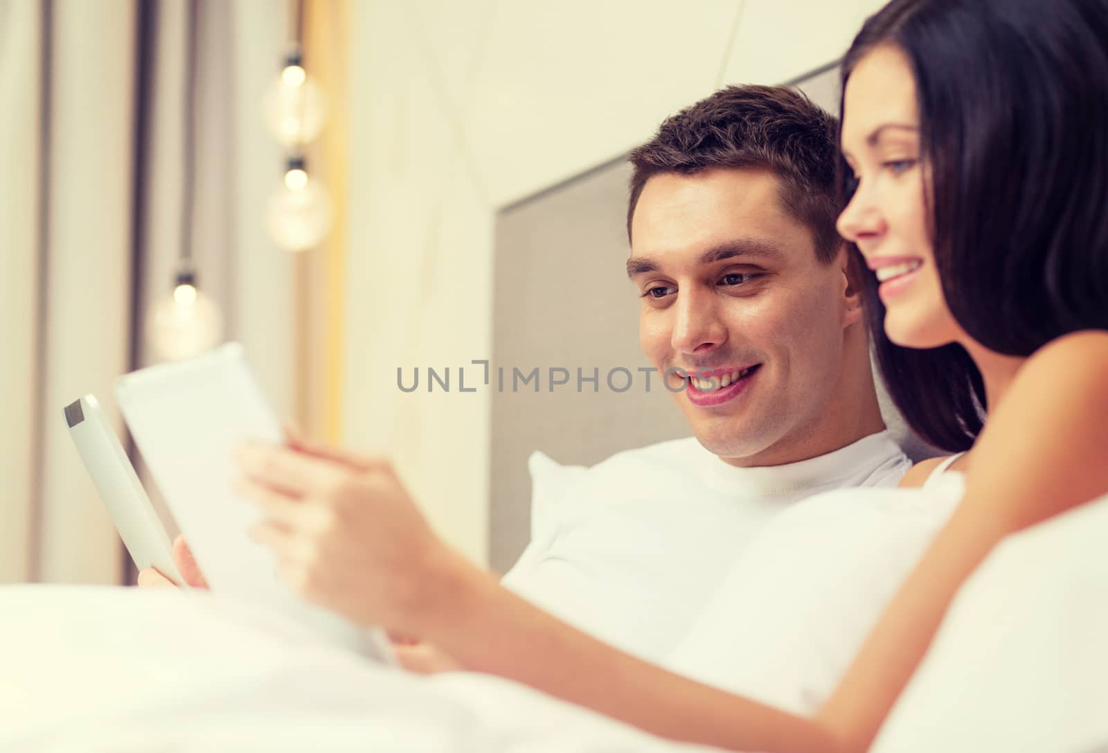 smiling couple in bed with tablet pc computers by dolgachov