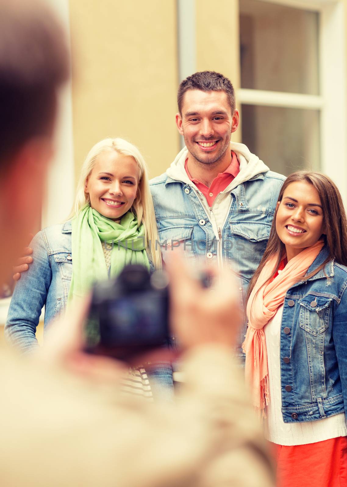 travel, vacation, technology and friendship concept - guy picturing group of friends in city