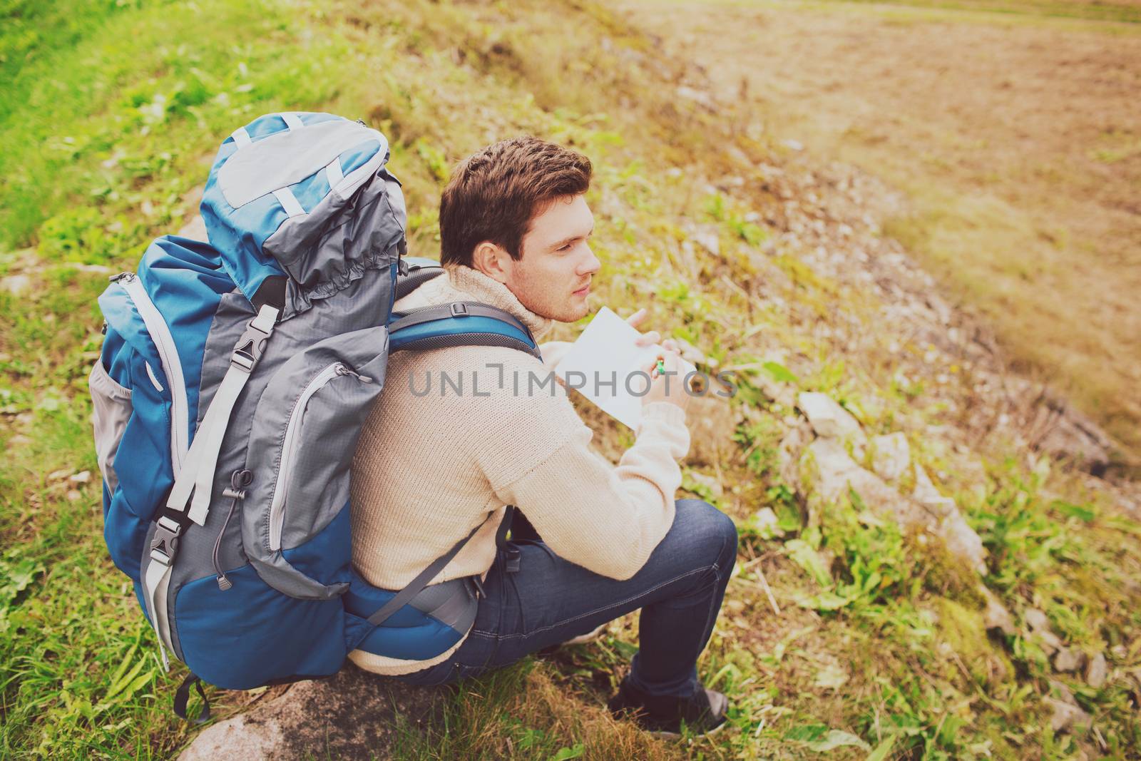 adventure, travel, tourism, hike and people concept - man with backpack sitting on ground from back