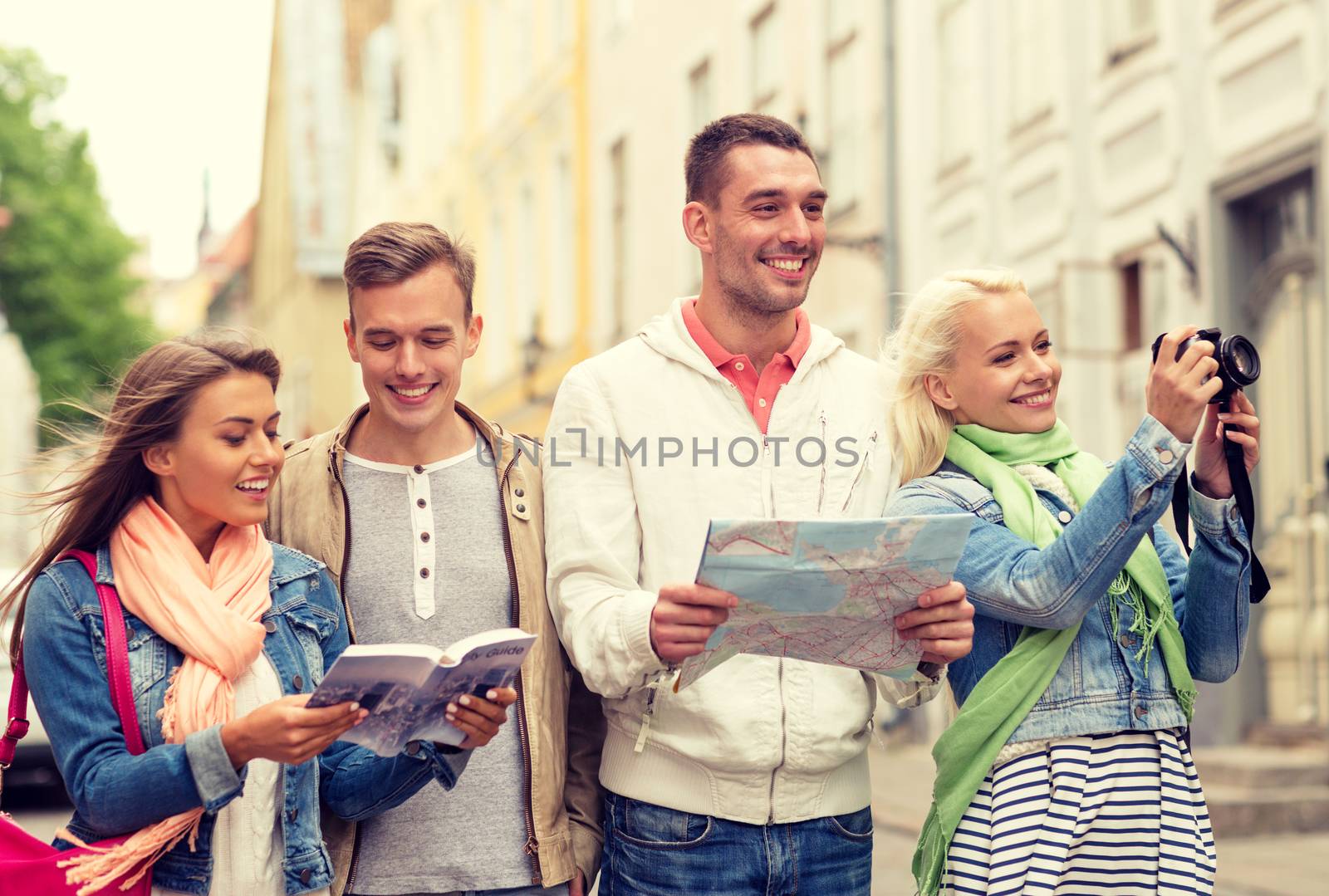 travel, vacation, technology and friendship concept - group of smiling friends with city guide, photocamera and map exploring city