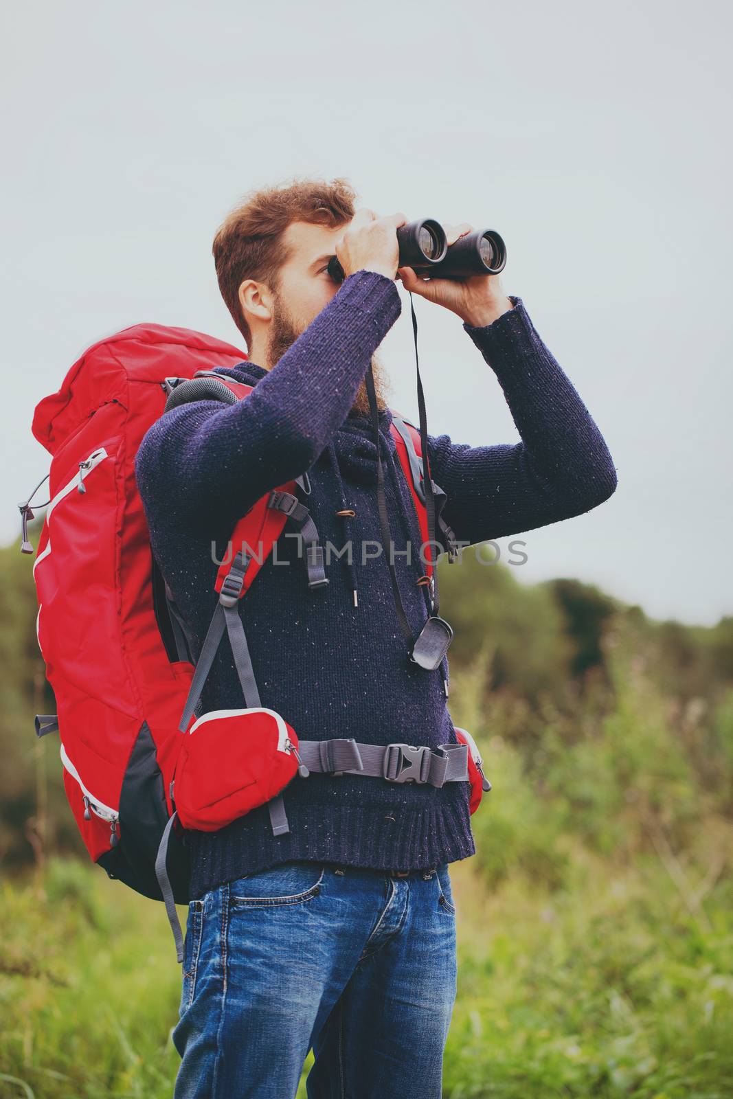 adventure, travel, tourism, hike and people concept - man with red backpack and binocular outdoors