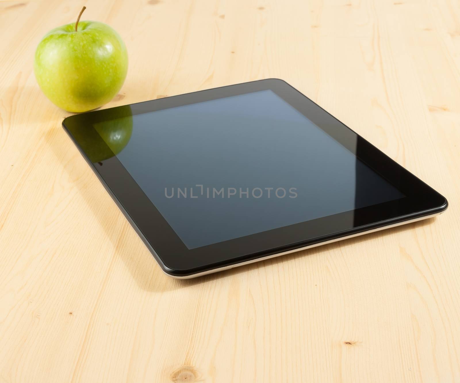 digital tablet pc near green apple on wood table by donfiore