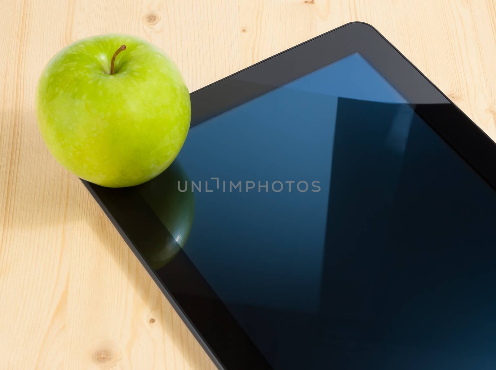 digital tablet pc and green apple on wood table by donfiore