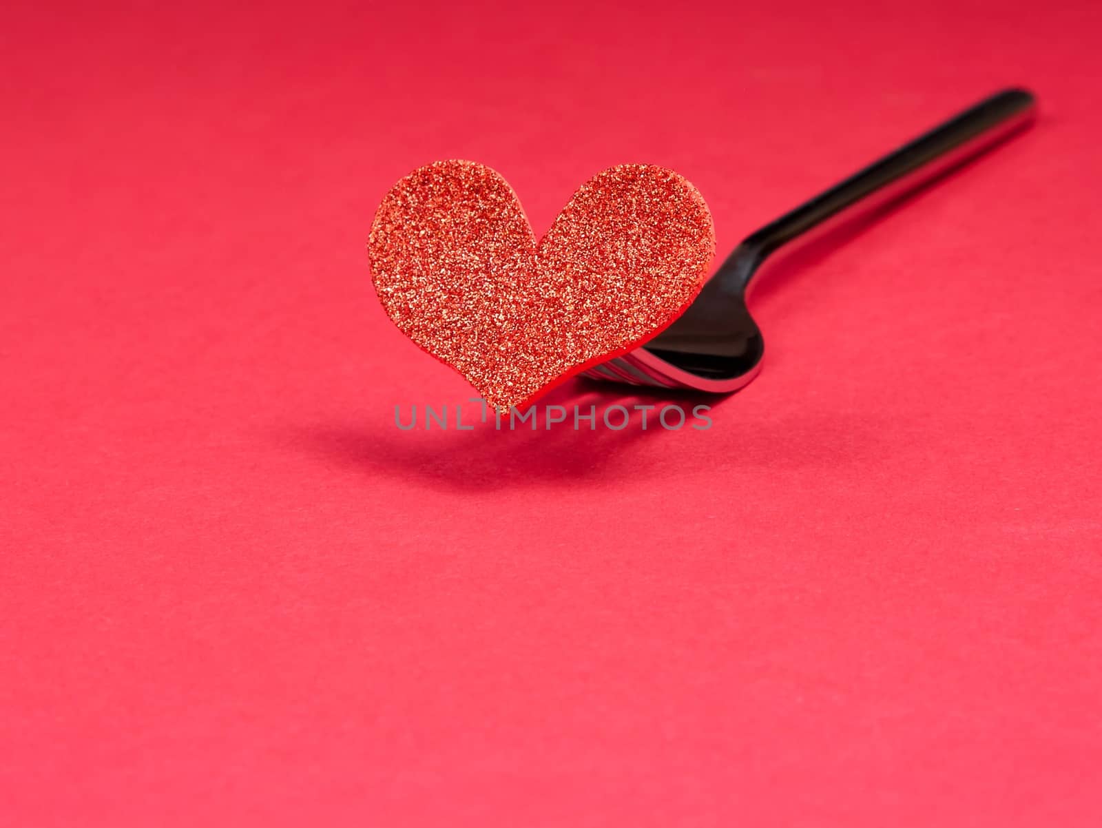 decorative red heart near a fork on red background with space for text, concept valentine day dinner 