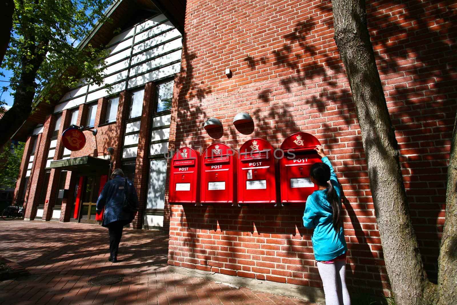 girl dropping a letter in a red postbox in denmark