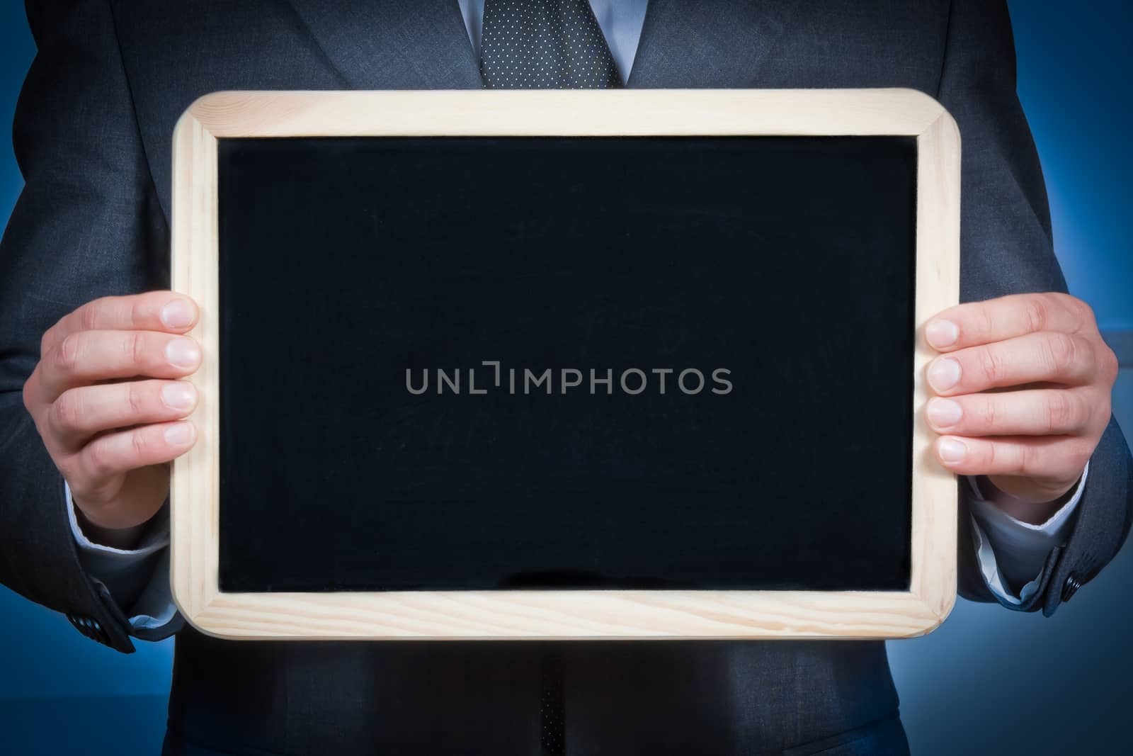 businessman holds a blank blackboard with the hands on a blue background