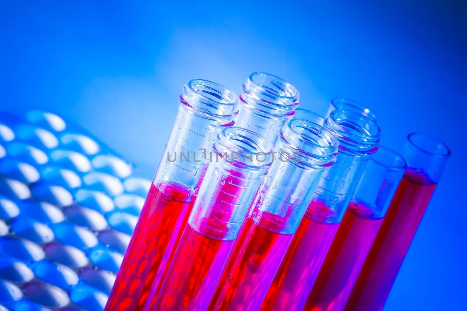 test tubes with red liquid in laboratory on blue light tint background