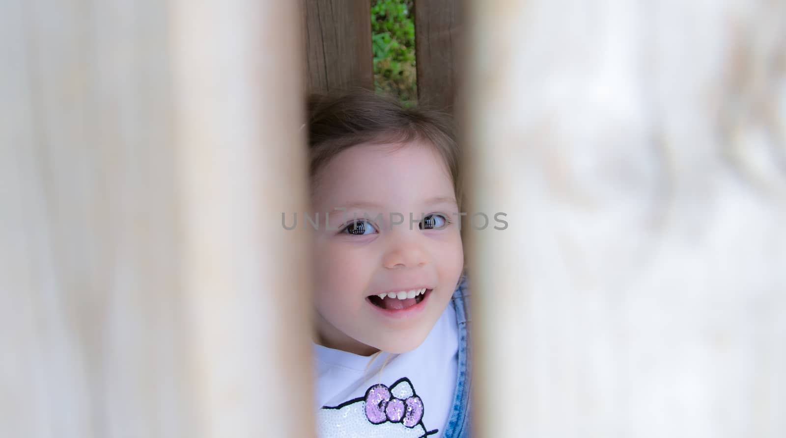 child laughs hidden behind a fence by Isaac74