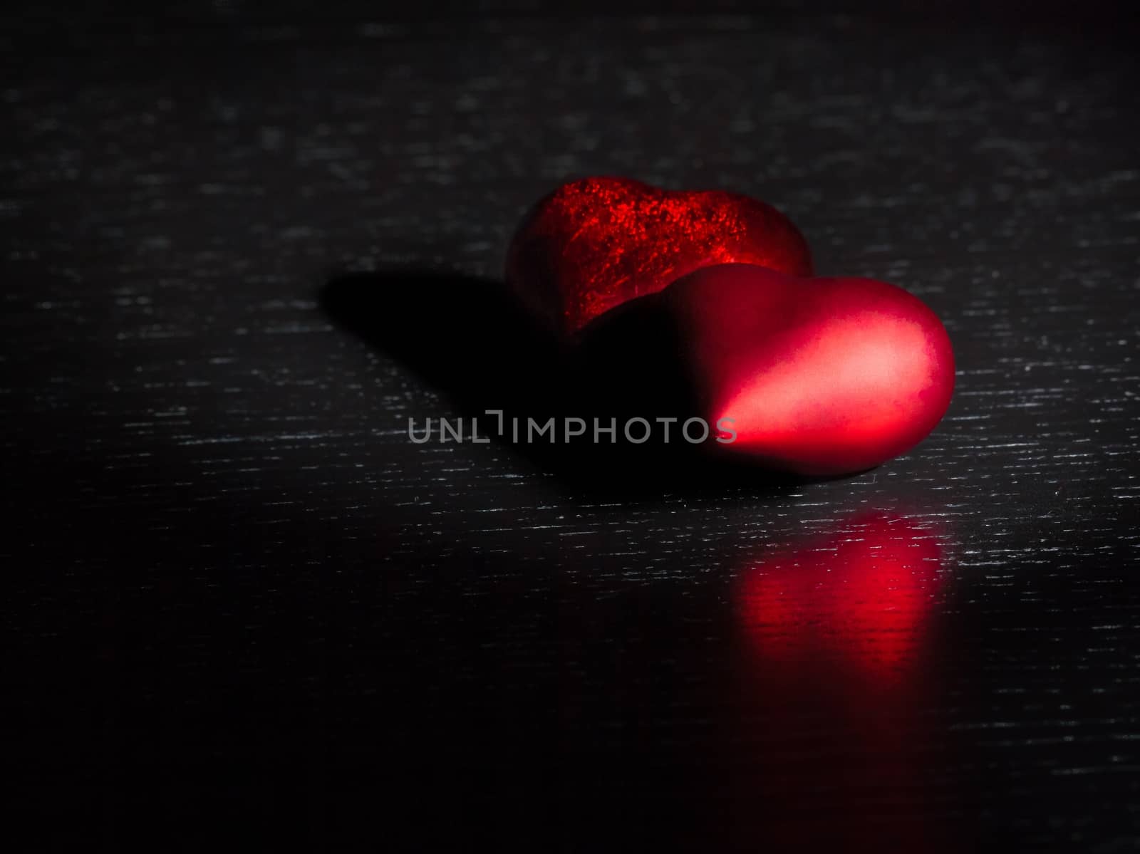 two decorative red hearts on black dark light and on wood table with space for text, concept of valentine day